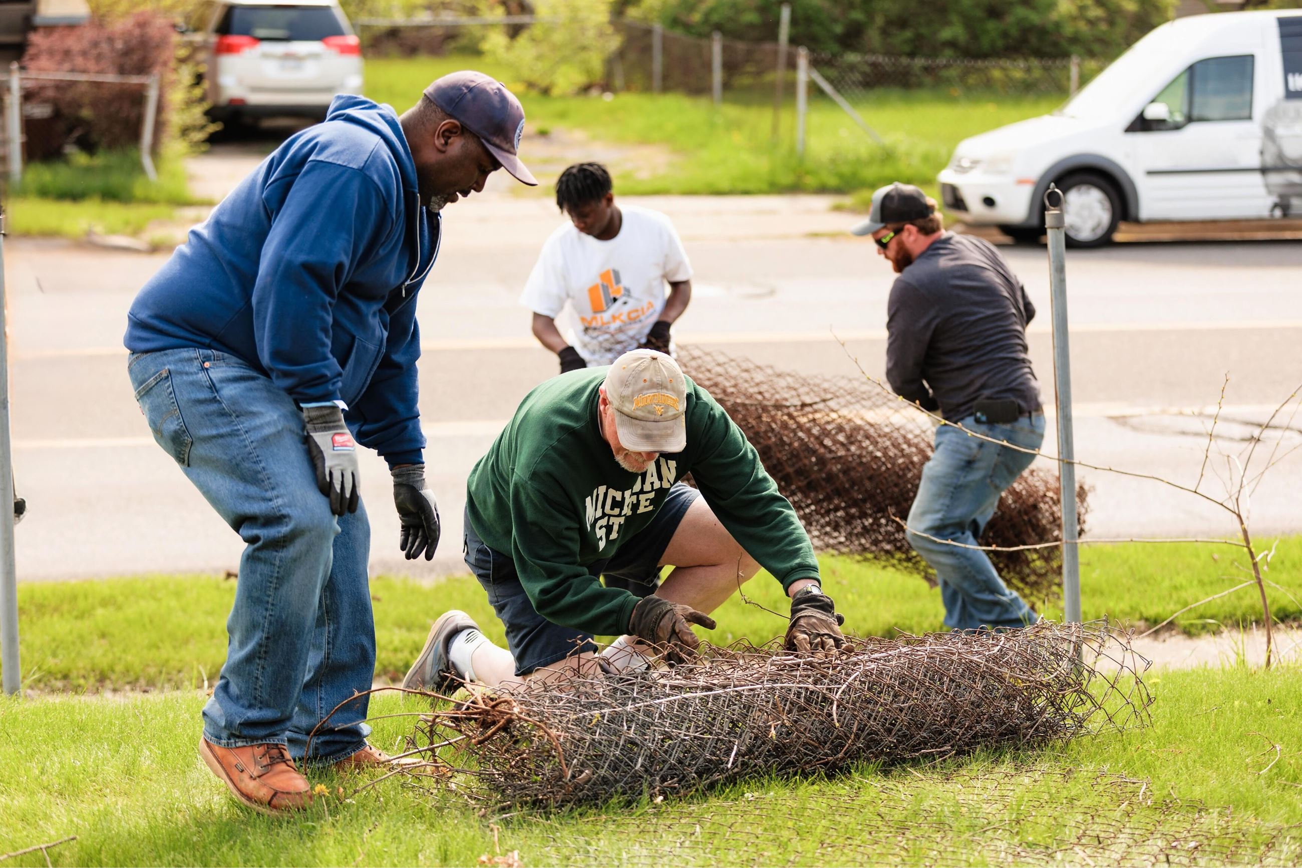Men remove old fencing on a green lawn