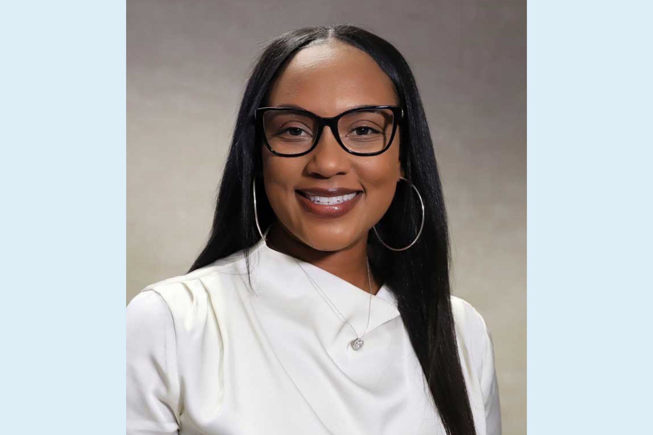 African American woman with long hair smiles wearing glasses and white shirt 