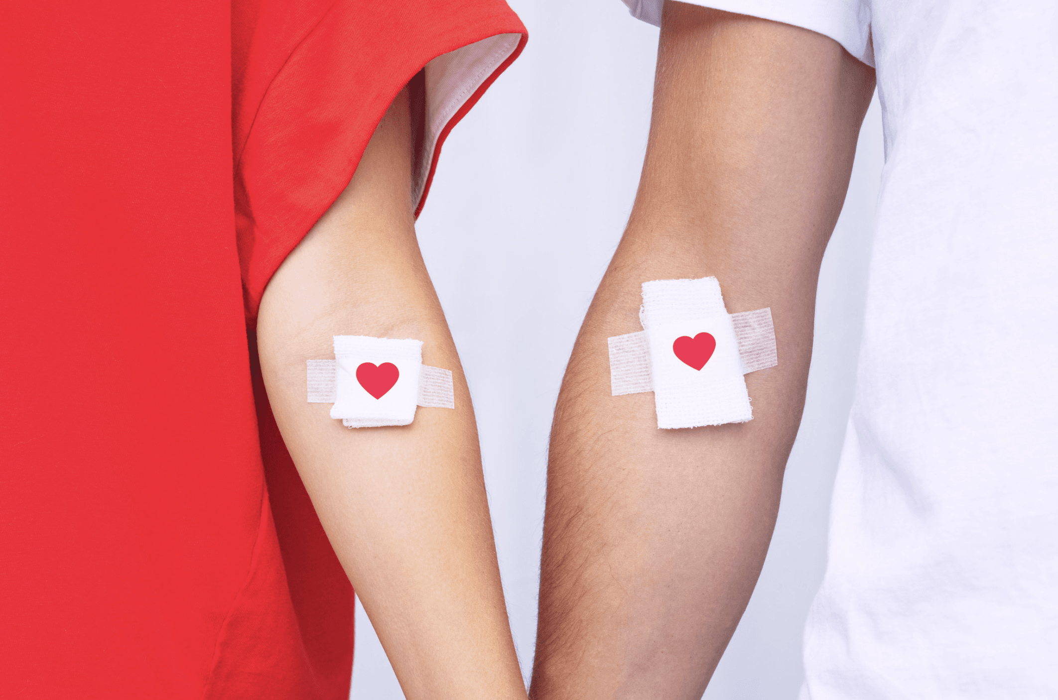 Two people stand next to each other with bandages covering their arms. 