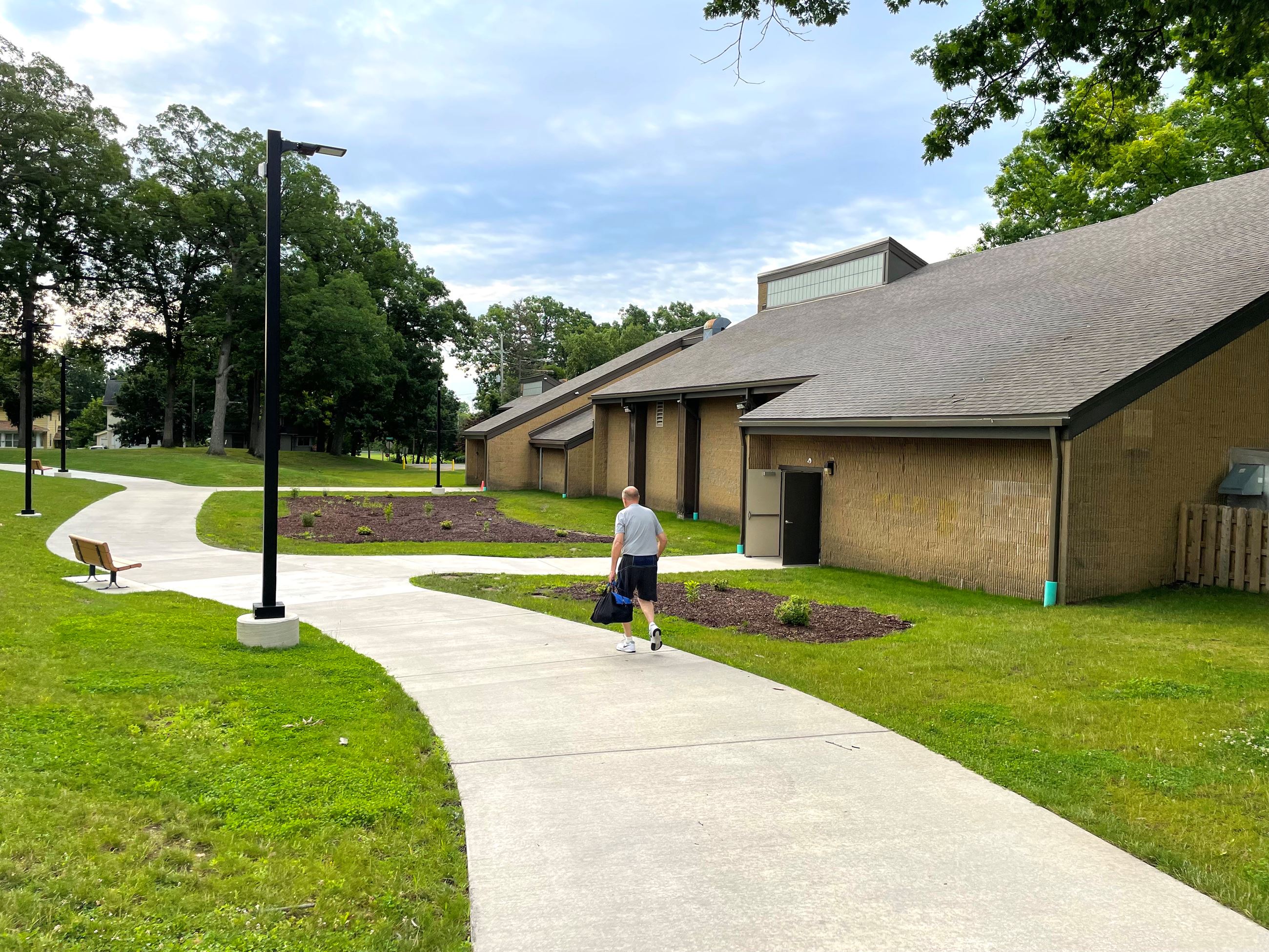 A while male carrying a gym bag walks into a new renovated brick recreation center