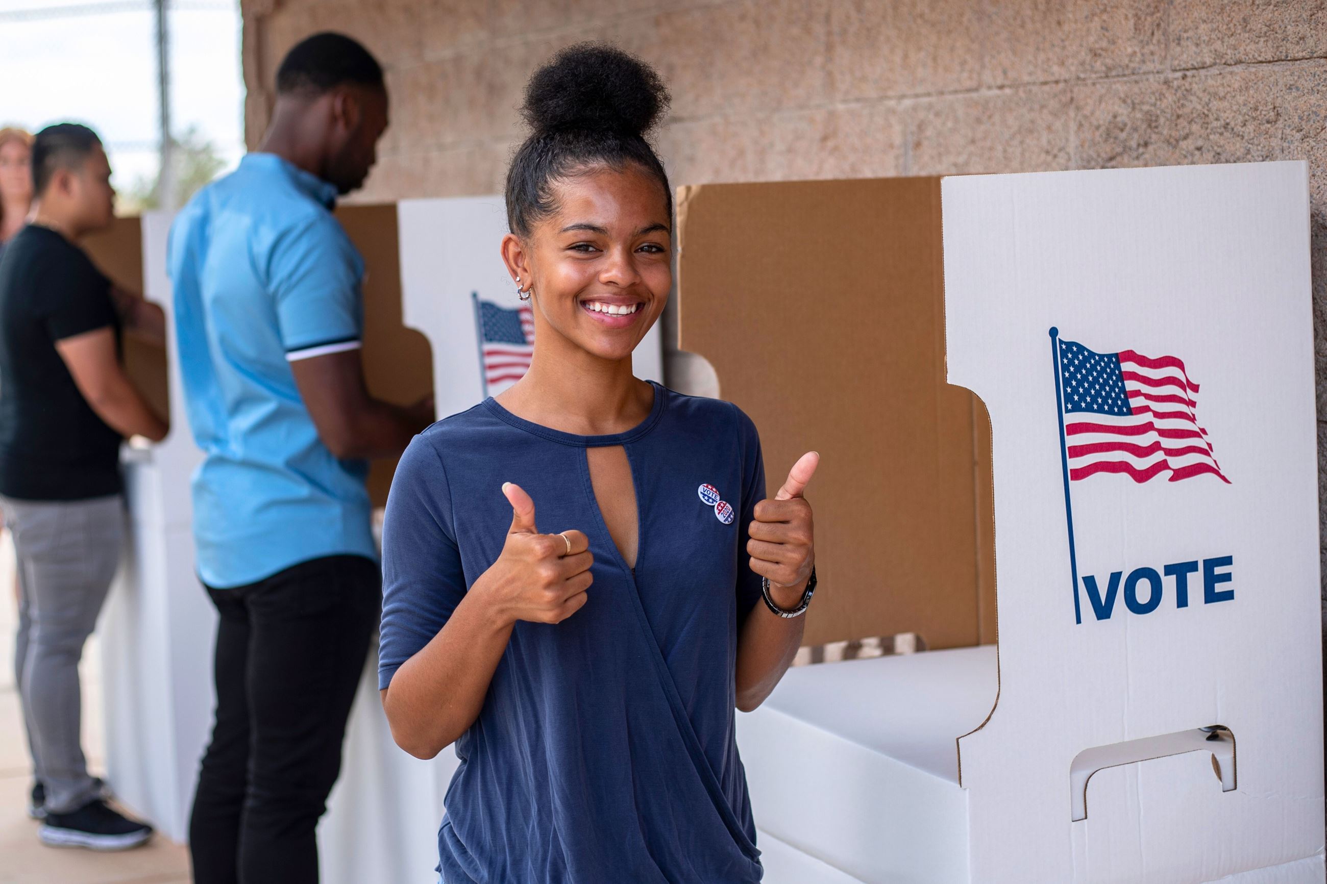 African American woman smiles and gives thumbs up after voting at polling place