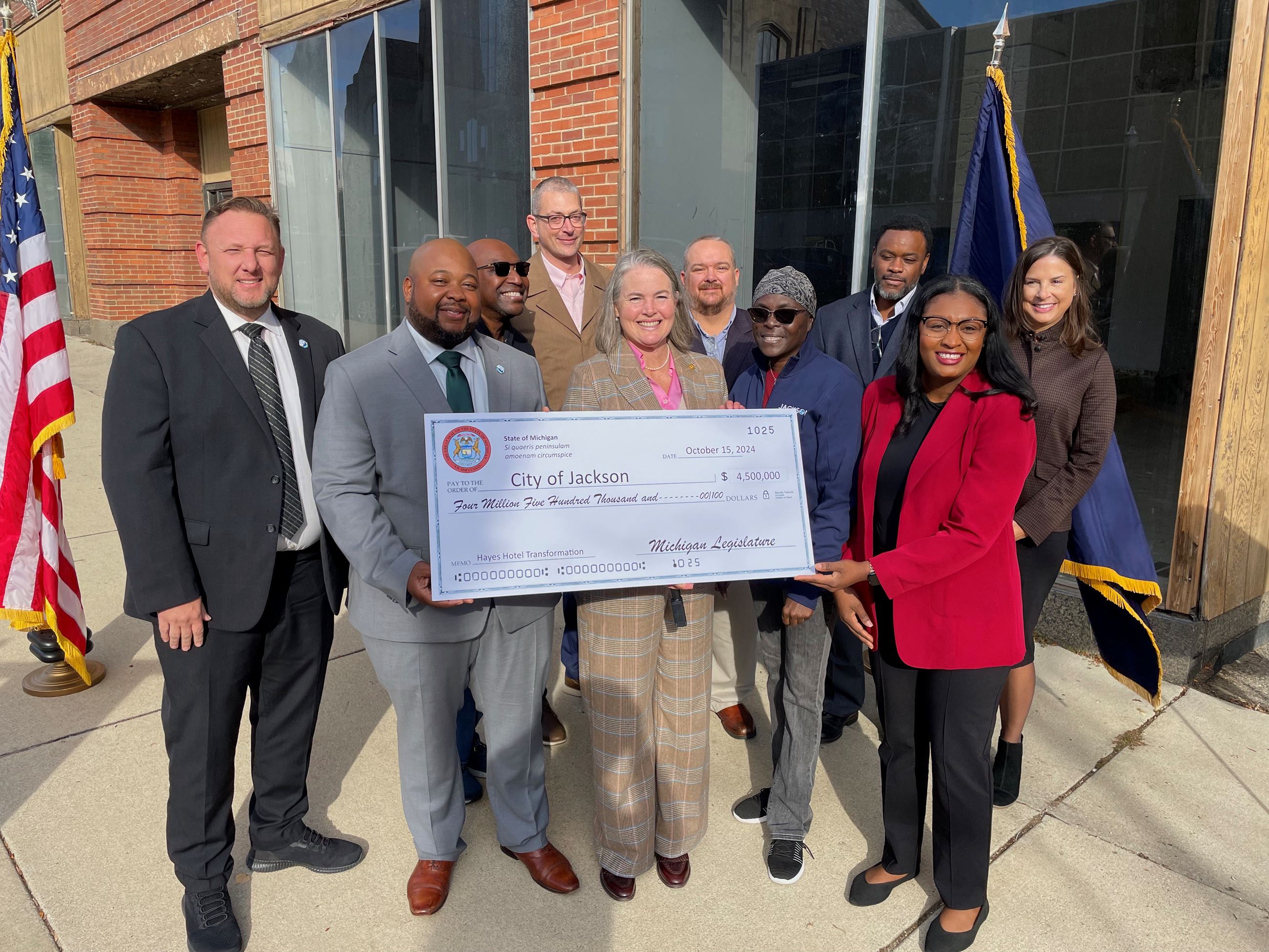 A group of men and women hold a large check for 4.5 million dollars 