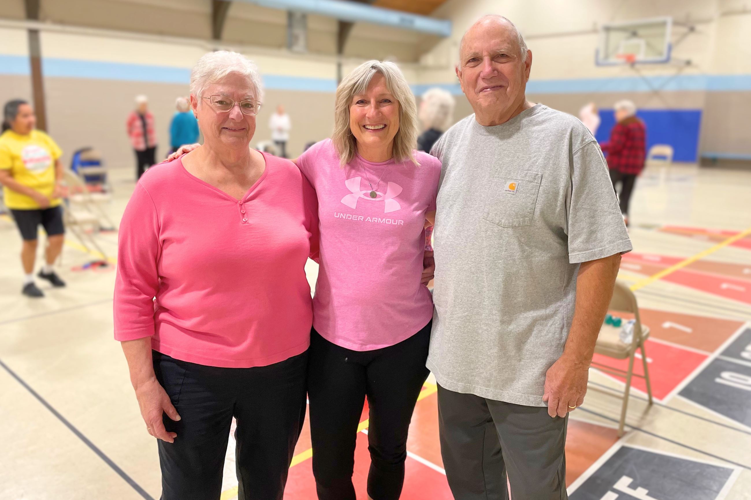 A woman in center is flanked by a man and woman. They're all smiling. 