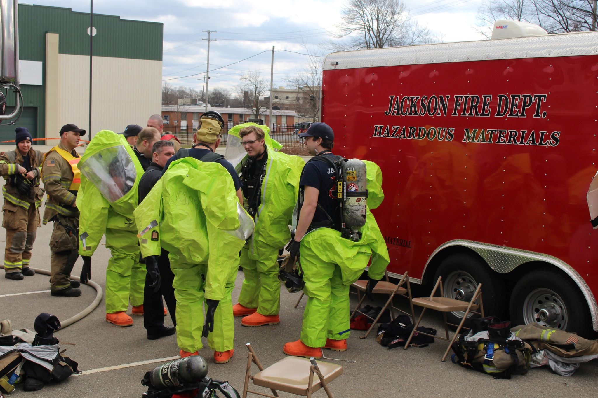 Firefighters in bright hazmat suits stand next to a red trailer that says jackson hazmat response 