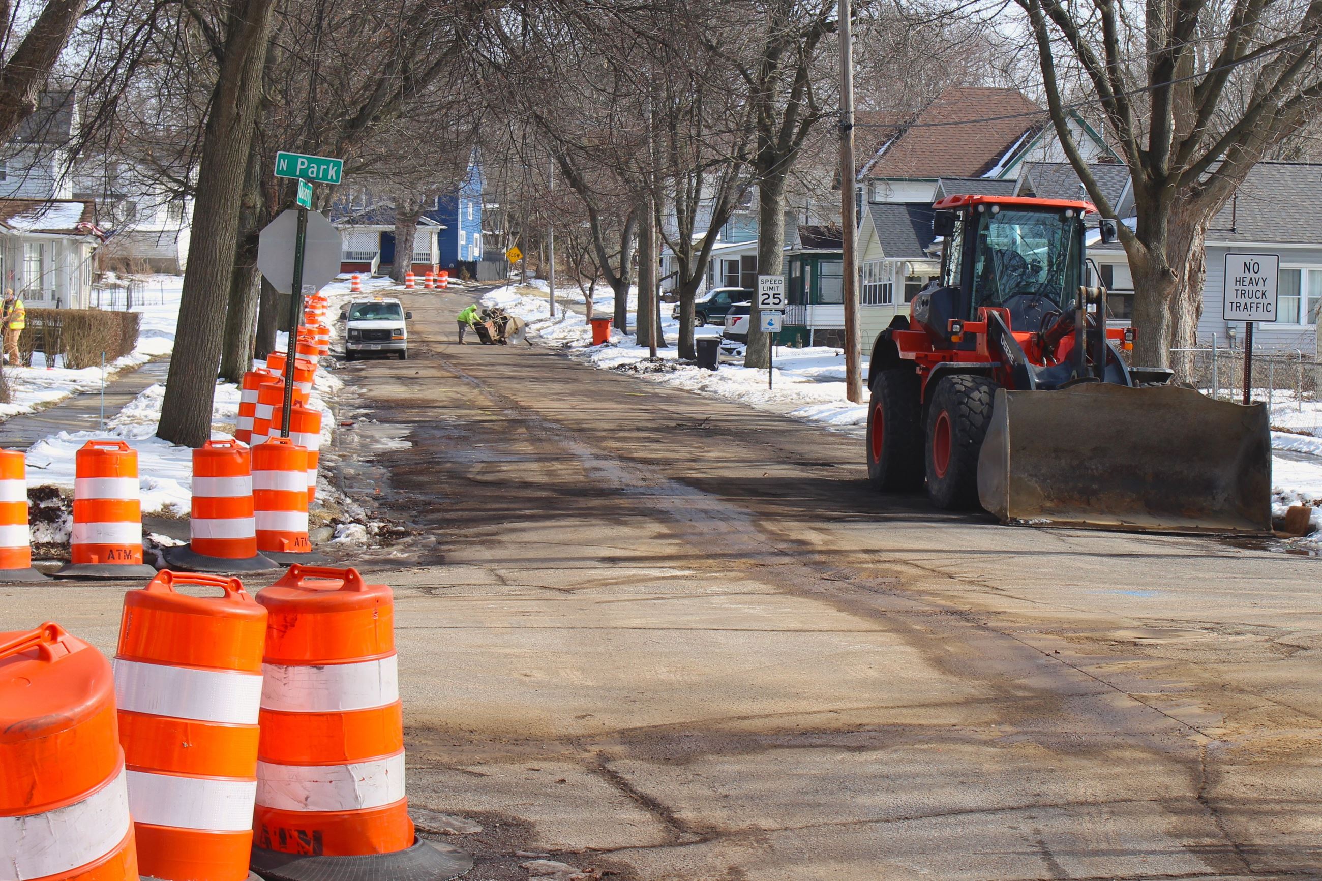 A neighborhood street with orange cones and construction equipment
